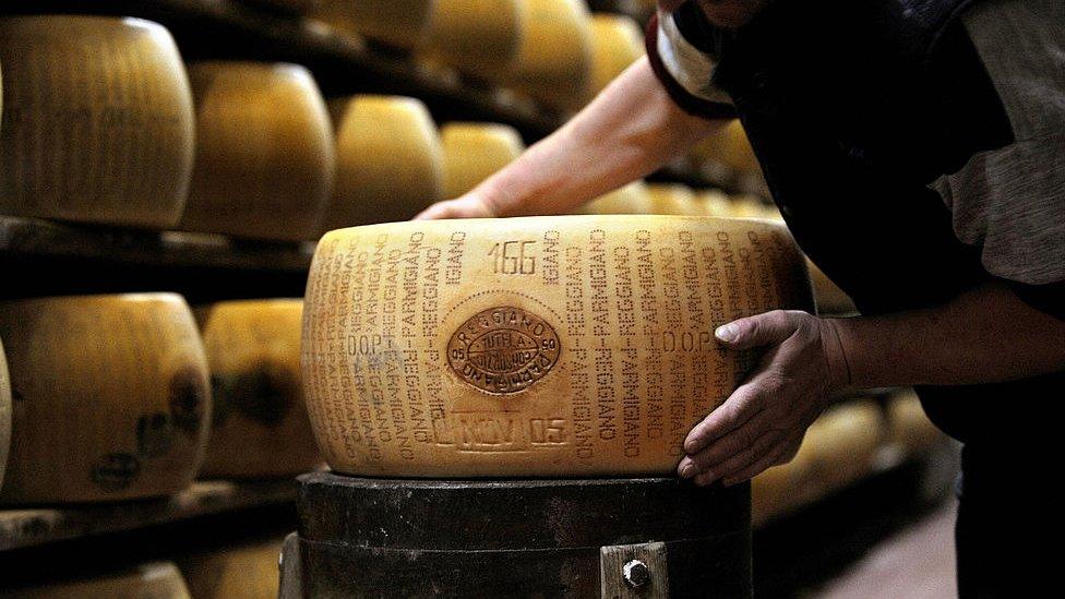 A picture taken on February 15, 2008 shows a worker checking a wheel of seasoned Parmigiano Reggiano cheese in a factory in Valestra, near Reggio Emilia