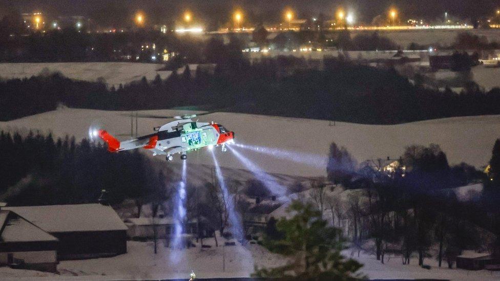 A person is lowered from a rescue helicopter near the site