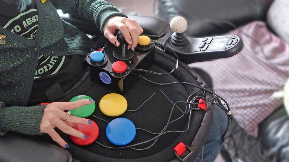 A person using a modified video games controller, with buttons and a joystick