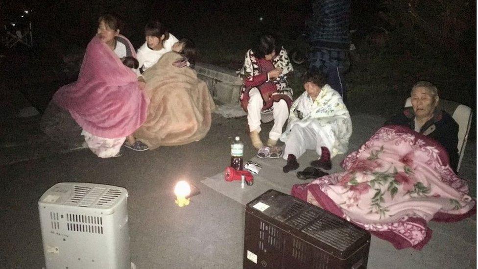 Residents wrap themselves in blankets on road in the town of Mashiki, in Kumamoto, southern Japan, after the earthquake early Friday, April 15, 2016.