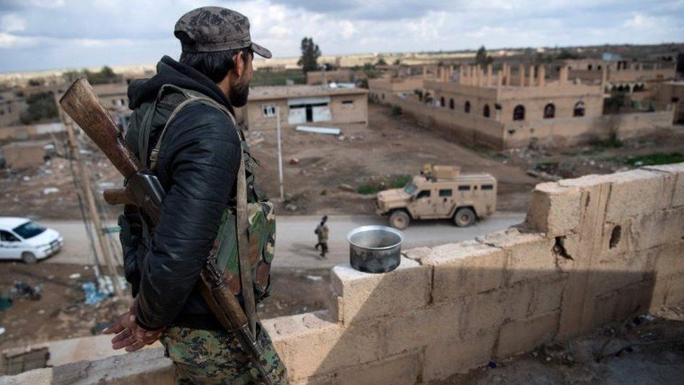 A member of the Syrian Defence Forces stands guard on top of a building in the frontline Syrian village of Baghuz, on 17 February 2019.