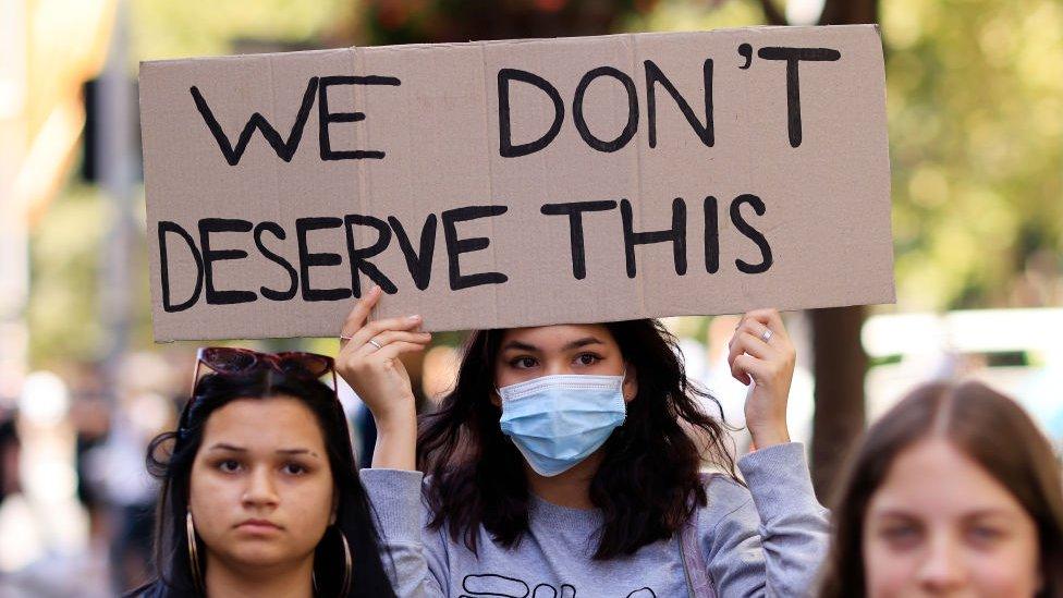 A girl holds up a placard as people march from Town Hall on March 15, 2021 in Sydney, Australia.