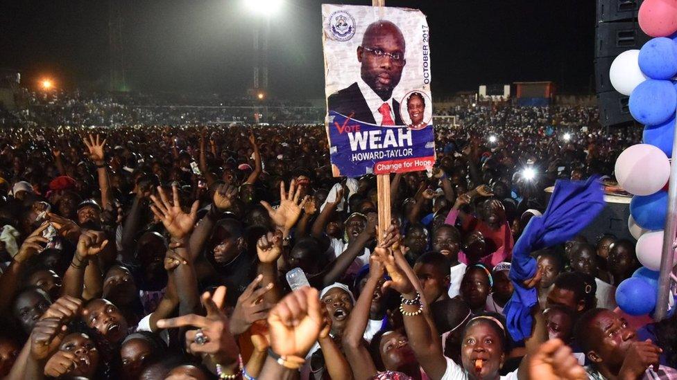 Supporters of former international Liberian football star turned politician George Weah wave during a presidential campaign rally in Monrovia on October 6, 2017