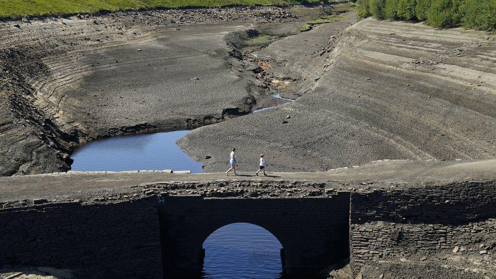 Two people walking across cracked earth at Ripponden, West Yorkshire