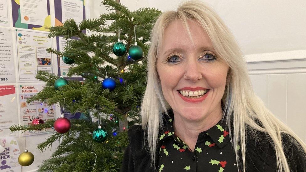 Jill Neighbour smiling at the camera with a Christmas tree behind her