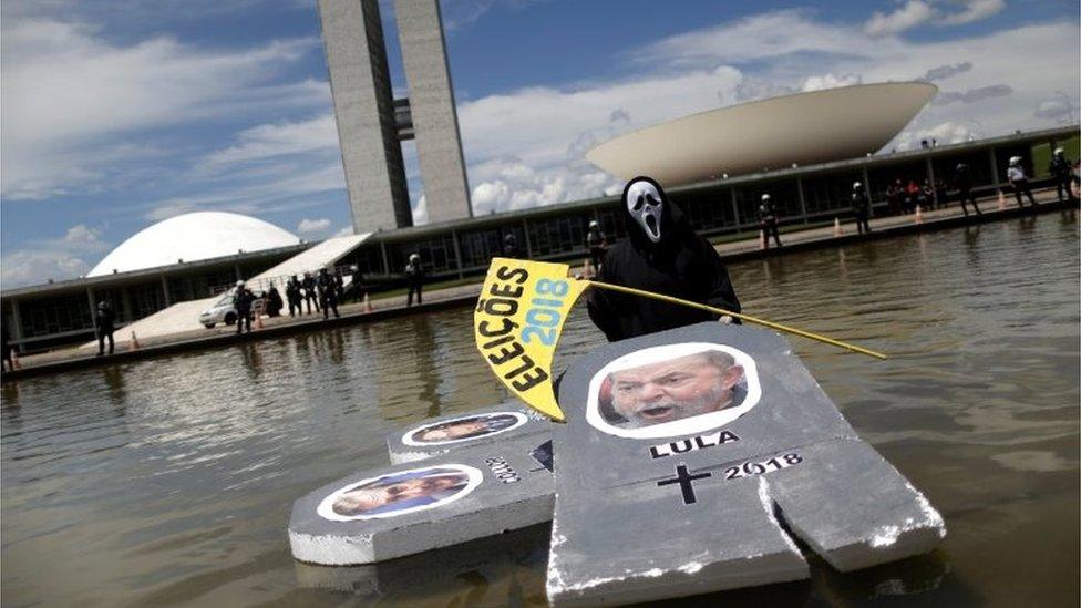 A protester wearing a mask is seen with an image of Brazil"s former president Luiz Inacio Lula da Silva, in front of National Congress during protest against corruption, in Brasilia, Brazil March 26, 2017.