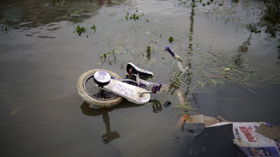 A child's bicycle floating in flood water