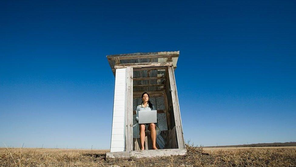 woman with laptop on outside toilet