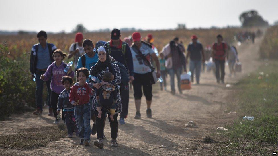 People walk through a field while moving towards Serbia"s border with Croatia, close to the town of Sid, Serbia, Saturday, Sept. 19, 2015.