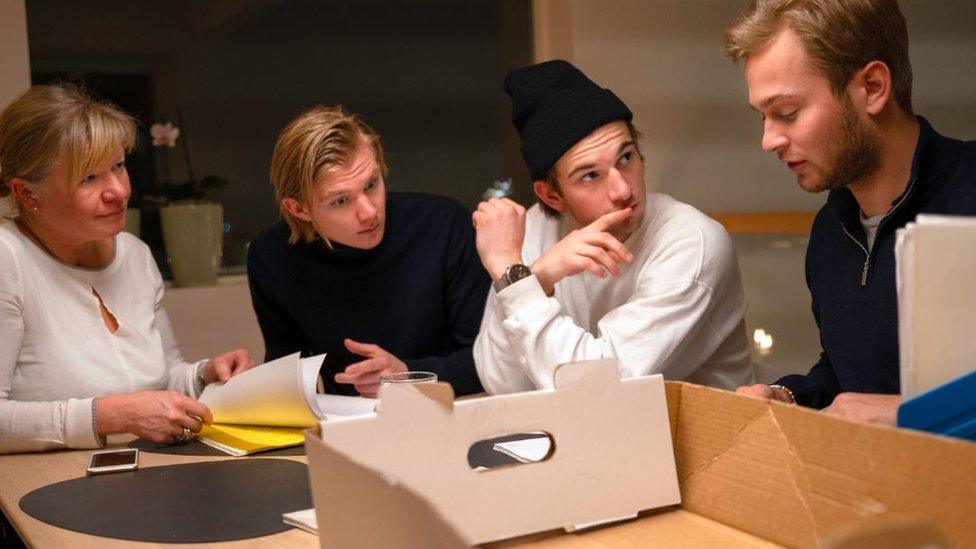 The members of the crime club sit around a table with boxes and papers on