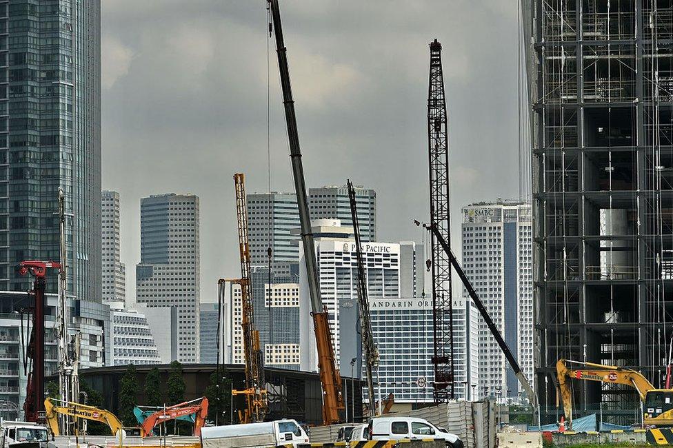 Under-constructed buildings (foreground) rise against the skyline (background) of the financial business district in Singapore on 18 January 2016.