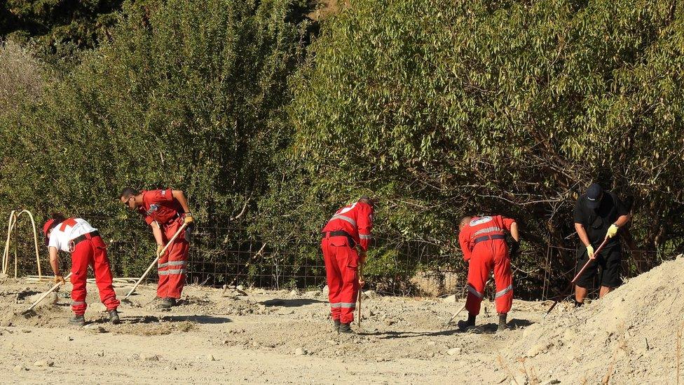 A South Yorkshire police officer (R) and members of the Greek rescue service (in red uniforms) investigate the ground while excavating a site for Ben Needham, a 21 month old British toddler who went missing in 1991, on the island of Kos, Greece