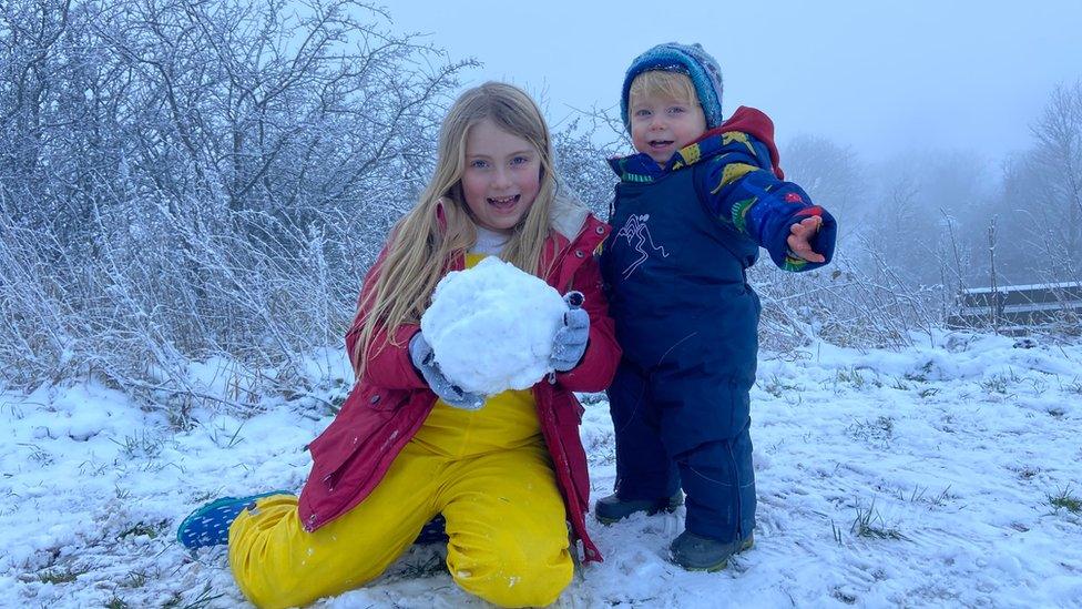 A boy and girl hold a snowball.