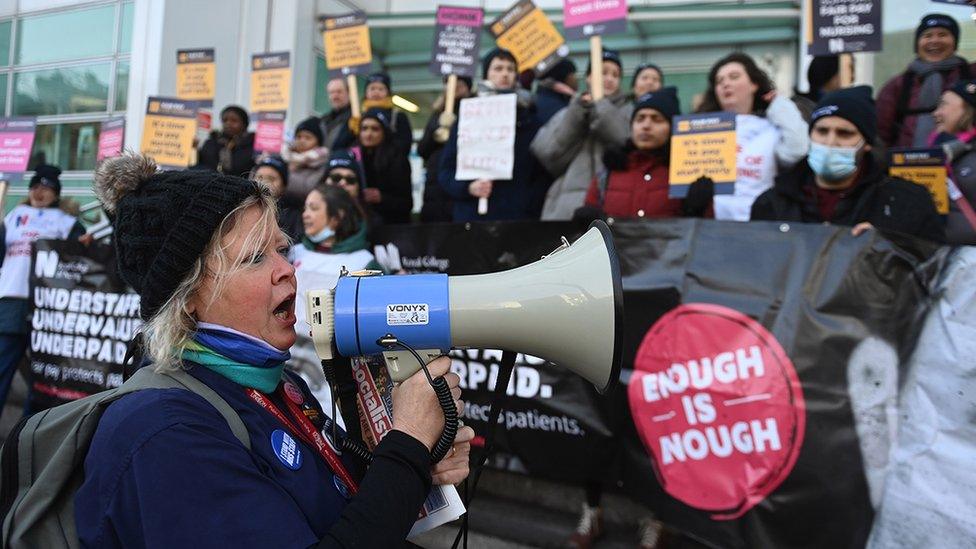 A nurse with a megaphone stands in front of the picket line outside University College Hospital in London