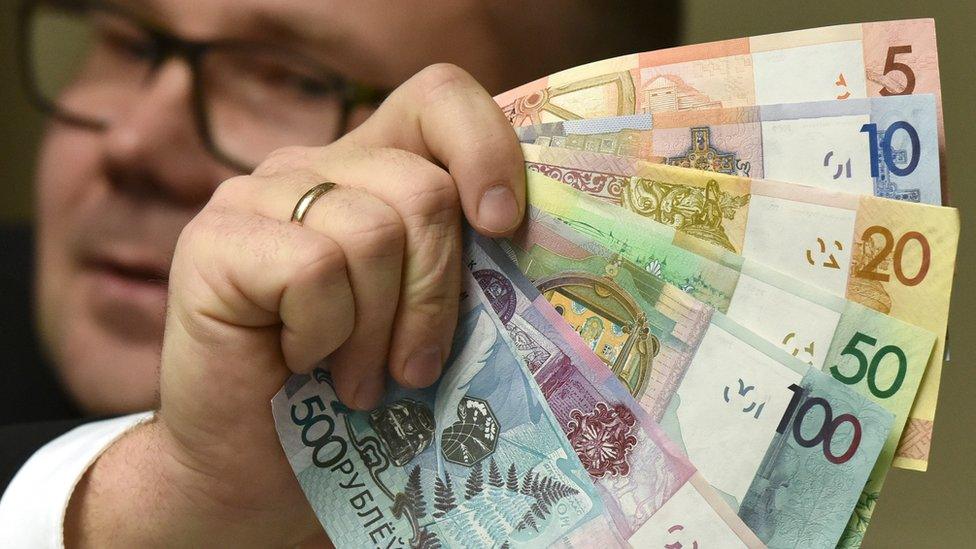 A man holding the new denominations of banknotes