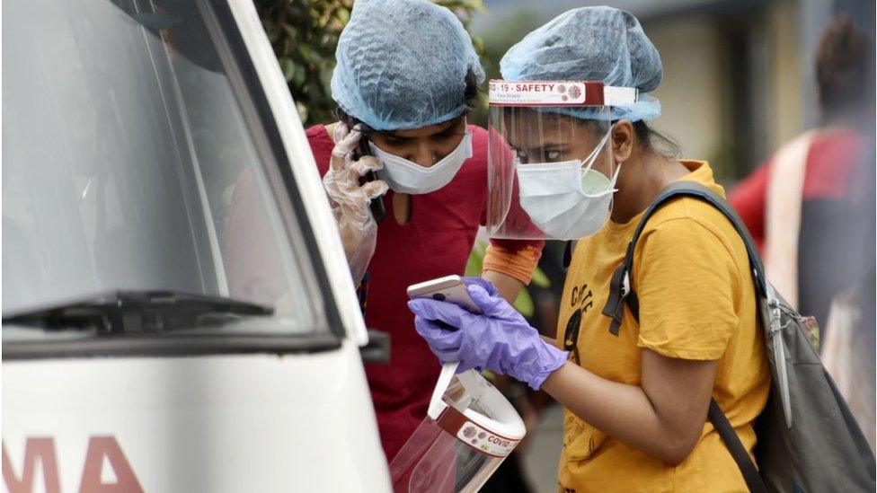 Family members of a Covid-19 patient talks on a mobile phone inside a government hospital