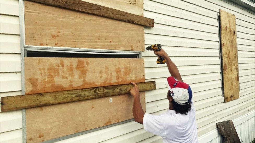 Man is pictured using drill to board up windows of his mobile home