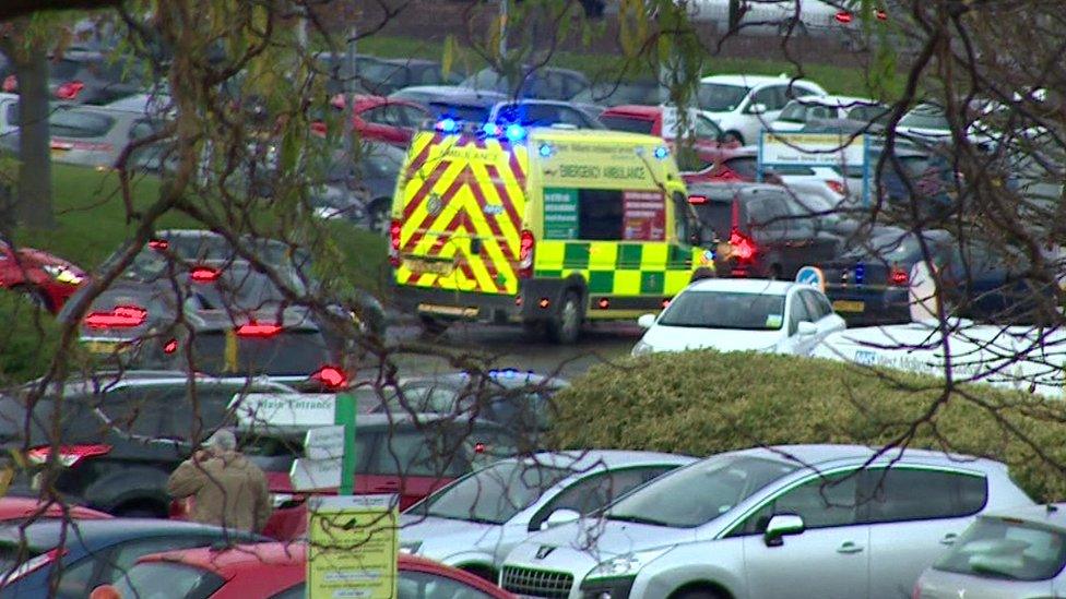 Ambulance in car park through trees