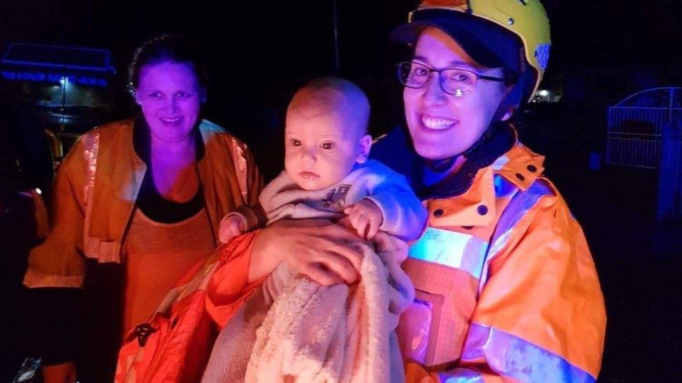 Emergency service worker holds up a baby rescued during Sydney floods