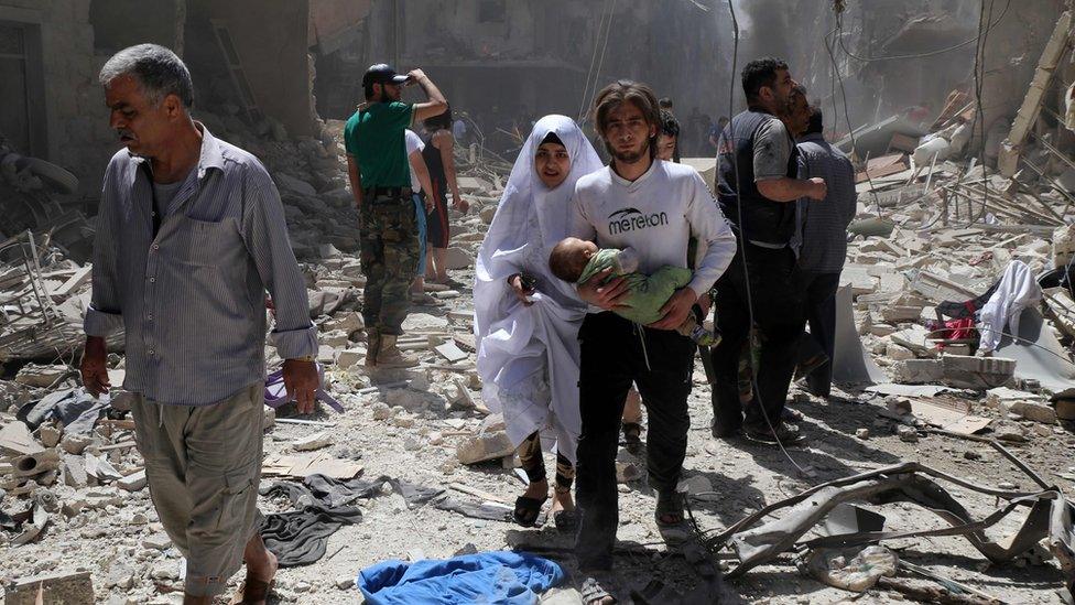 Syrian family amid rubble of destroyed buildings in Aleppo on April 28, 2016