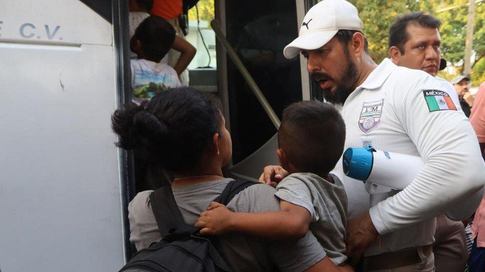 A migrant holding her son talks with an official from the National Migration Institute (INM) before boarding a bus, after finishing a migrant caravan heading to the United States, in the municipality of Mapastepec, state of Chiapas, Mexico, 02 January 2024