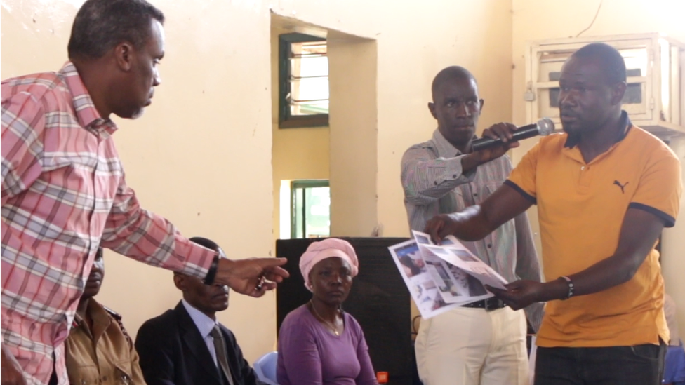 Wilfred Olal hands over print outs to the state prosecutor Noordin Haji (l)