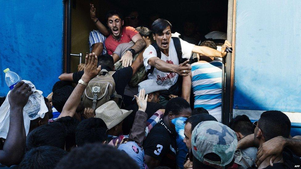 Migrants attempt to get on a train at the Macedonian-Greek border