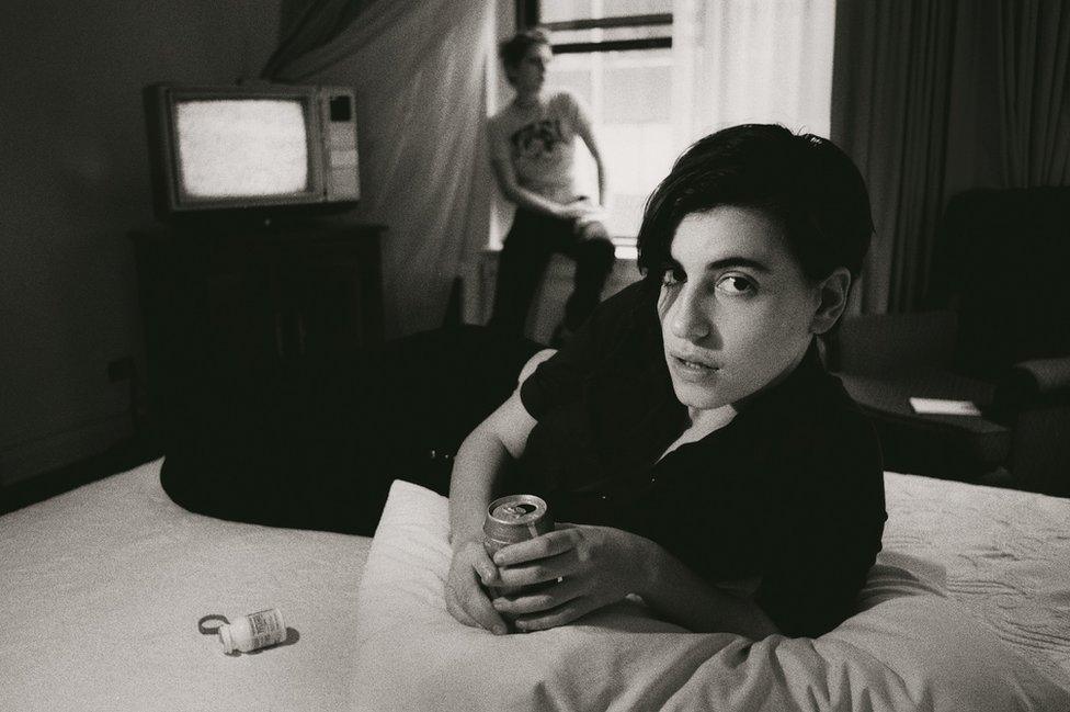 Elastica's Justine Frischmann on a hotel bed drinking a can of lager