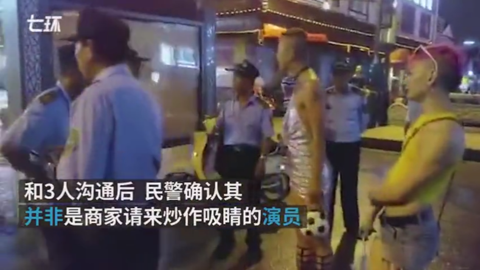 A man in drag argues with a police officer on a street in the Chinese city of Suzhun