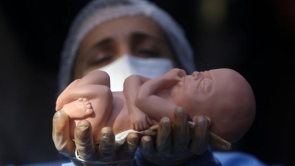 An anti-abortion activist demonstrates holding a doll in the vicinity of the constitutional court in Santiago (21 August 2017)