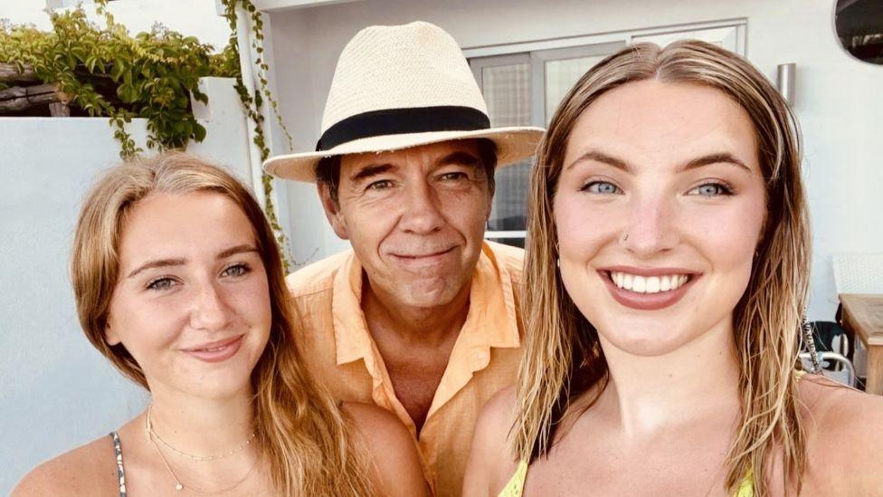 A man in a fedora and two women smile for a selfie