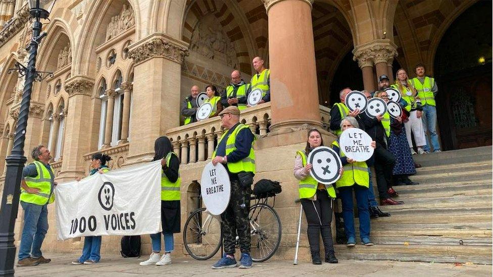 People in hi-viz vests with placards standing on Guildhall steps