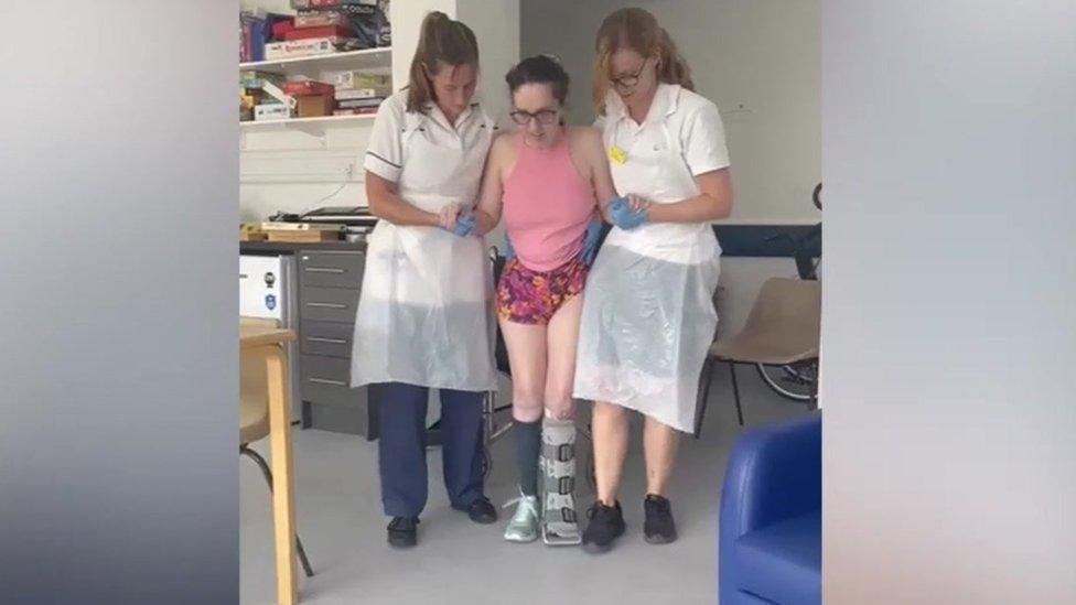 Rebecca Sharp helped by two nurses as she walks in hospital