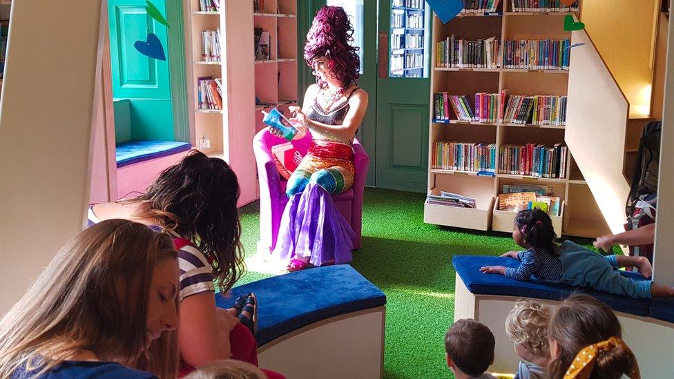 Sab Samuel as Aida H Dee reading to children in a library