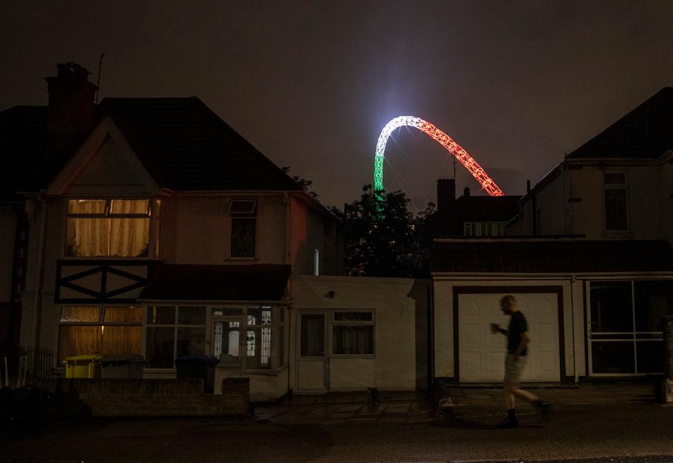 A fan leaves Wembley as the Wembley arch is lit in the colours of the Italian flag following their win during the UEFA Euro 2020 Championship Final between Italy and England at Wembley Stadium on July 11, 2021 in London, England.