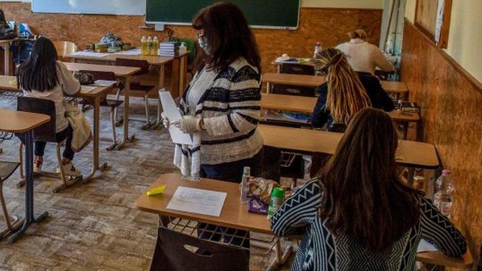 A teacher hands out papers at Szerb Antal Grammar Schools in Budapest, Hungary, 04 May 2020