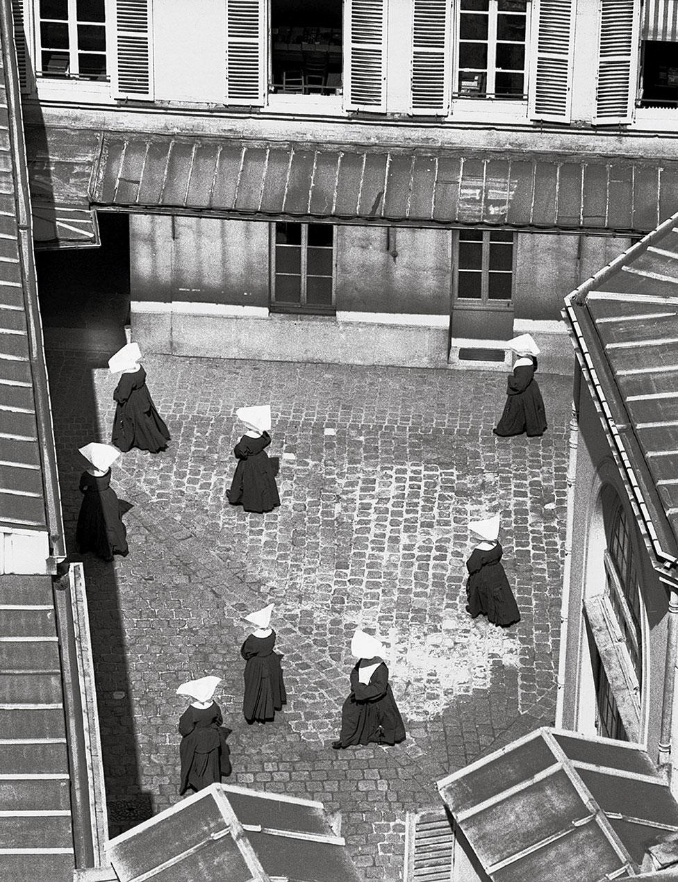 A group of nuns walk around a courtyard