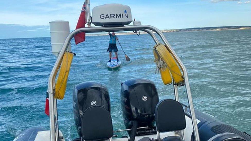 Joe Cartwright on a paddleboard by his support boat on the English Channel