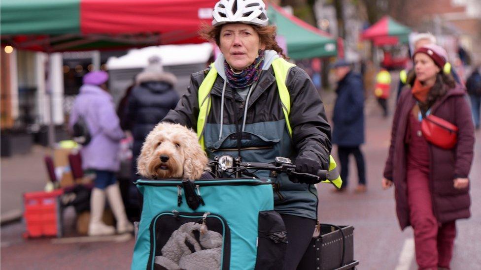 Woman cycling on Botanic avenue with her dog