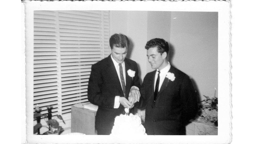 Two men cut wedding cake