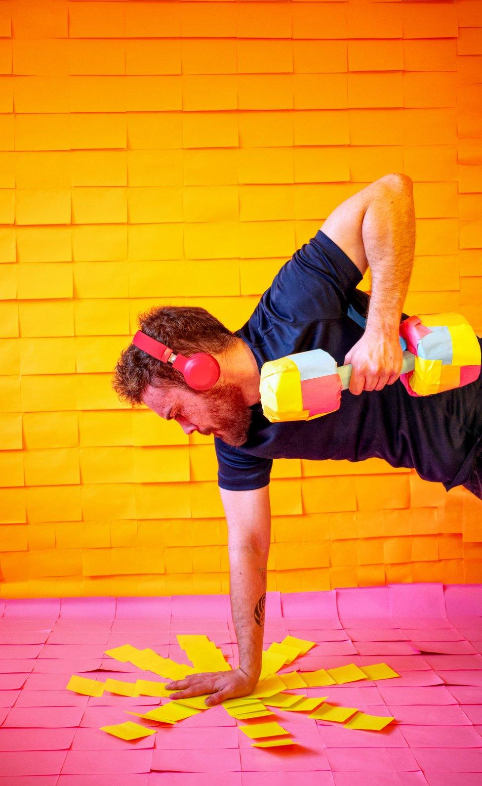 A man exercises surrounded by colourful post-it-notes