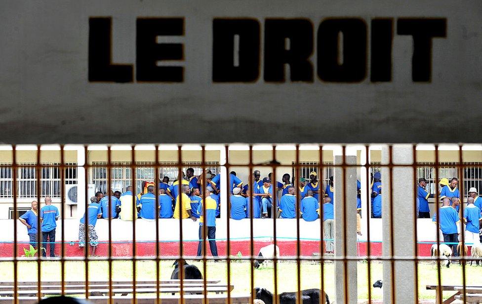 Prisoners are seen at the Makala prison in Kinshasa on December 18, 2012 from behind the bars of the windows of a court room.