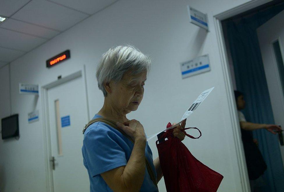 An elderly woman looks at a medical certificate outside a consulting room at a hospital in Beijing on 3 July 2014.