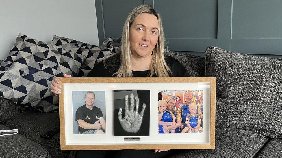 Janet holds up a memorial photo frame of her fiancé Paul