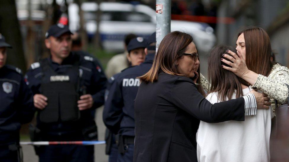 Teachers console students near the school in Belgrade