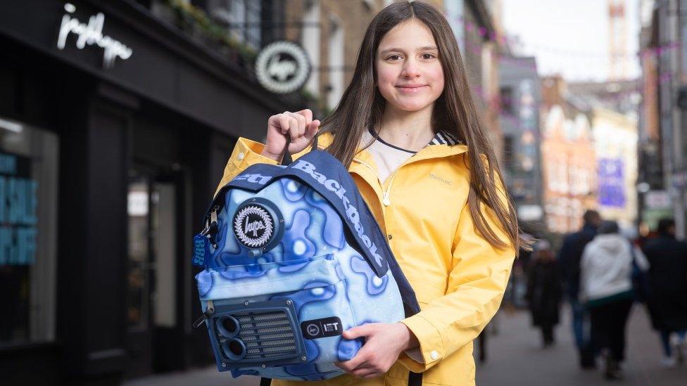 Eleanor holding her rucksack, with visible air filter on the front