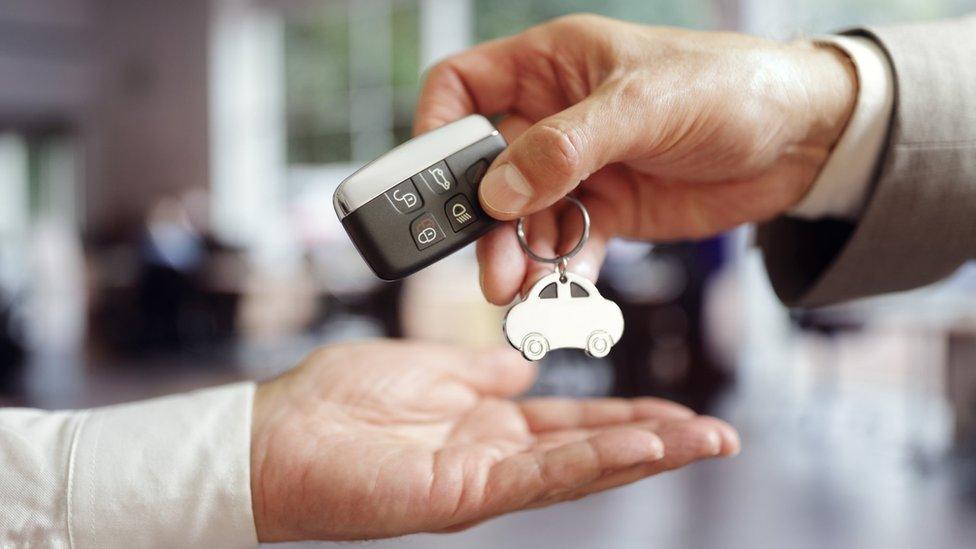 Man handing car keys to another man