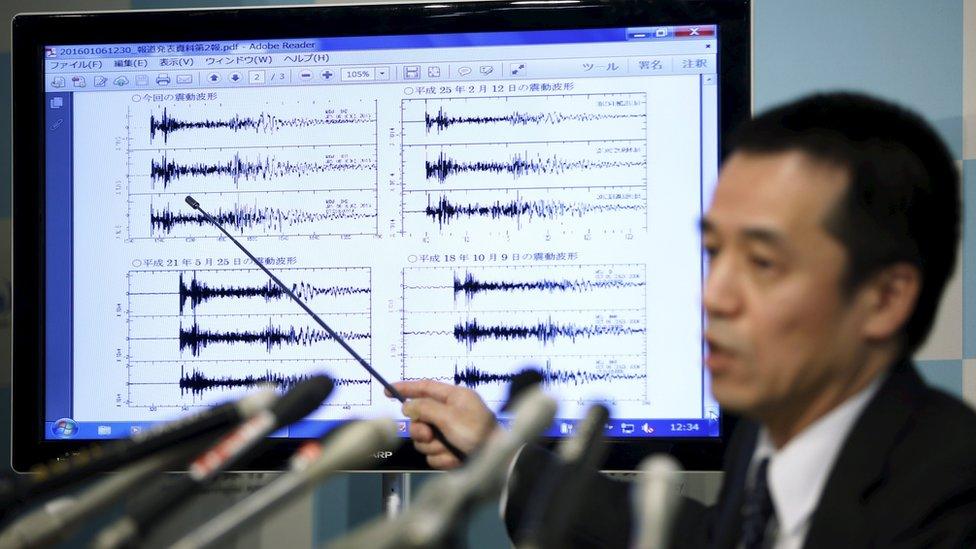 Japan Meteorological Agency's earthquake and tsunami observations division director Yohei Hasegawa points at a graph of seismic data