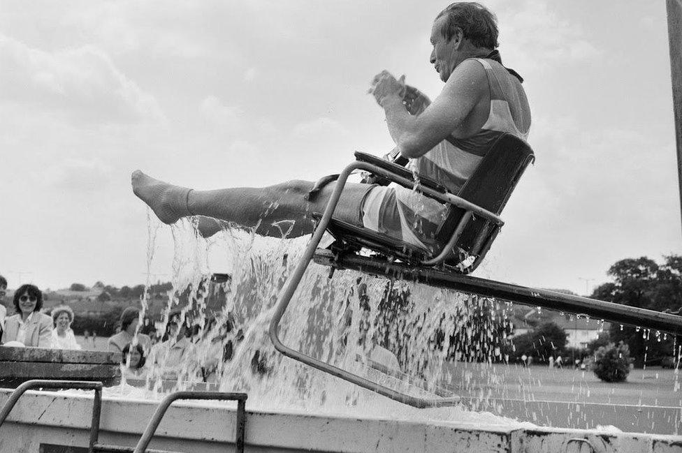 Director being dunked into pool in chair