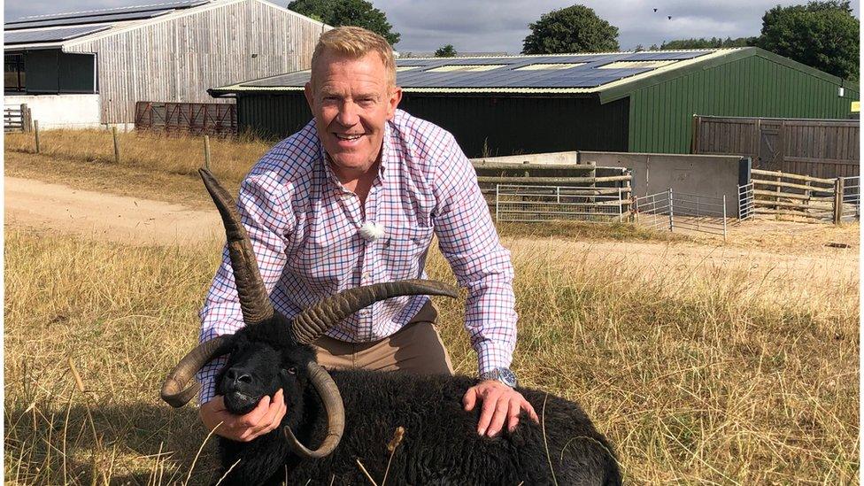 Adam Henson on the Cotswold Farm Park in front of a barn with solar panels